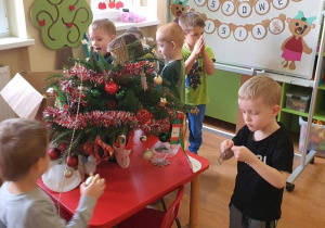 Dzieci wspólnie tworzą dekorację świąteczną.